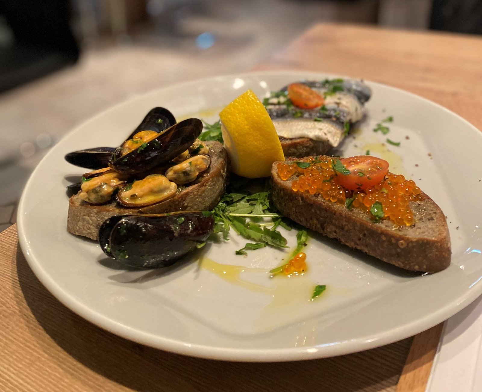 Brot mit Muscheln, Kaviar und Sardinenfilets, serviert mit Zitronenspalte